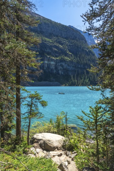 Tourists are canoeing on the turquoise, glacier fed moraine lake with the scenic valley of the ten peaks in the background in banff national park, canadian rockies, alberta, canada
