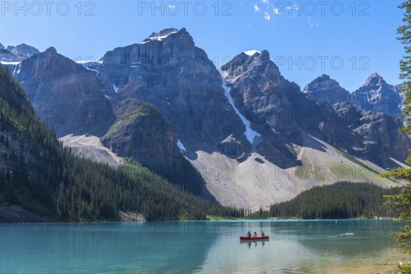 Breathtaking turquoise waters of moraine lake reflecting majestic mountains and glaciers in banff national park, with tourists enjoying canoe rides on a sunny day