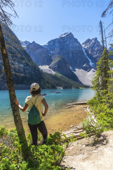 Female tourist with backpack enjoying the breathtaking view of moraine lake and the valley of the ten peaks on a sunny summer day in banff national park, canadian rockies, alberta, canada