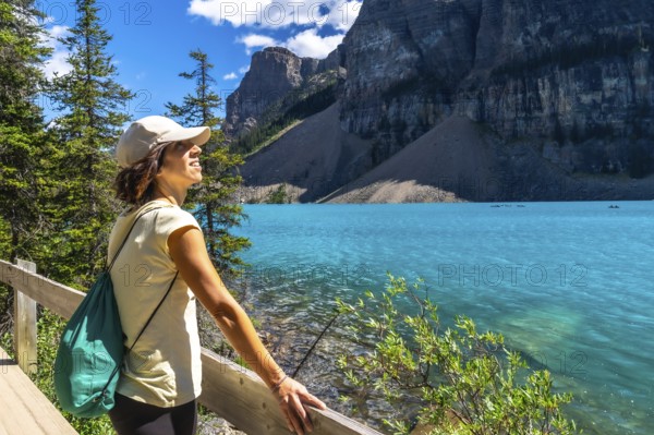Female tourist admiring the turquoise waters of moraine lake, with the stunning valley of the ten peaks in the background, in banff national park, alberta, canada