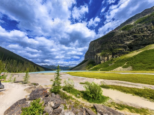Moraine lake in banff national park showcases turquoise waters surrounded by the valley of the ten peaks and lush vegetation, creating a stunning panorama under a cloudy sky