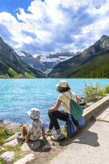 Mother and child are enjoying the breathtaking view of the turquoise waters of lake louise. Surrounded by the majestic canadian rockies in banff national park. Alberta. Canada. On a sunny summer day