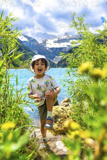Young child having fun by the turquoise waters of lake louise with the majestic rocky mountains in the background, enjoying a sunny summer day in banff national park, alberta, canada