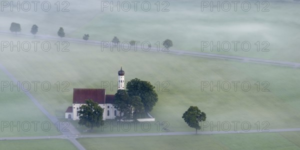 St. Coloman pilgrimage church in front of sunrise in autumn fog, Königswinkel, Ostallgäu, Allgäu, Bavaria, Germany