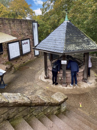 Tourists look down into a covered well shaft of 176 meters deep deepest castle well in the world Fountain of medieval imperial castle Kyffhausen next to Barbarossa monument, Kyffhäuser nature park Park, Thuringia, Germany