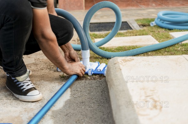 Pool suction hose installation. Person connecting pool hose handle. Man connecting the handle on the pool vacuum. Suction equipment connection for swimming pool