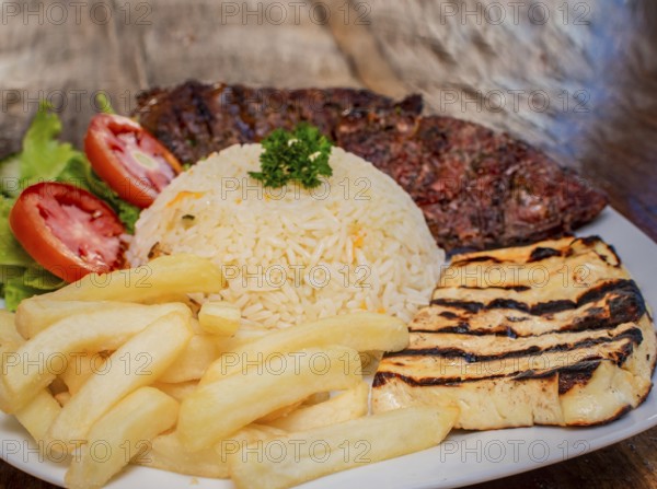 Close-up of roast beef with tomato salad and french fries, traditional barbecue roast beef food served on wooden table, plate with roast beef and salad served on wooden background