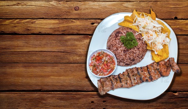 Roast beef dish with gallo pinto and pico de gallo, Roast beef with tomato and gallo pinto salad served on a wooden table, Plate with roast beef and rice served on a wooden table, Nicaraguan food