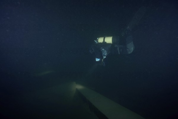 Diver examines a lediwreck, wreck of a lediship, ledi ship, cargo ship for mass freight, bulk cargo, at night in Lake Walen. Tauchplatz Känzeli, Mols, Canton of St. Gallen, Switzerland