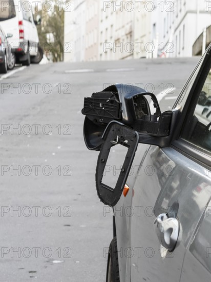 A car on the side of a steep residential street. The vehicle's left wing mirror is severely damaged and part of the mirror is on the hood, Wuppertal, Germany