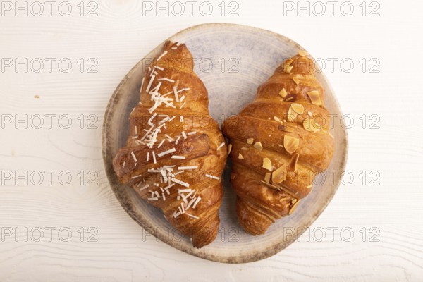 Croissant on blue plate on white wooden background, top view, flat lay, close up