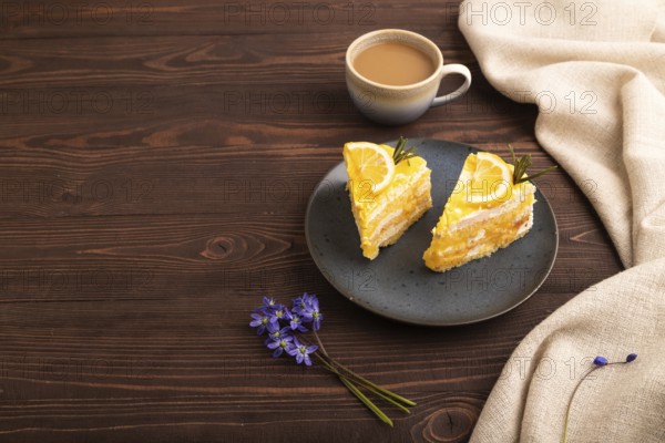 Lemon cake on brown wooden background and linen textile, cup of coffee, side view, copy space