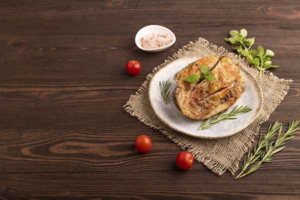Fried Turkey Thigh with spices and rosemary on plate on brown wooden background and linen textile. side view, copy space