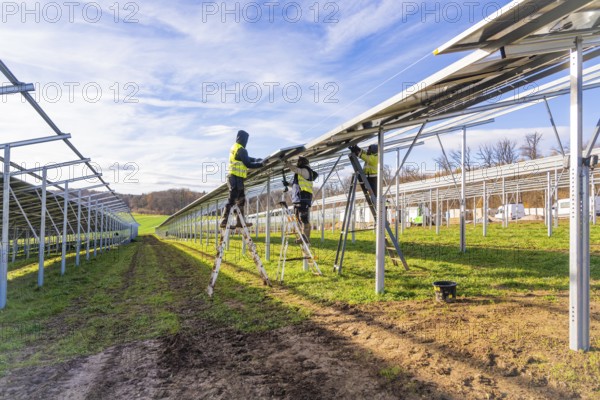 Workers install solar panels on a sunny day, Energiewende, construction of PV open space, Baden-Württemberg, Germany