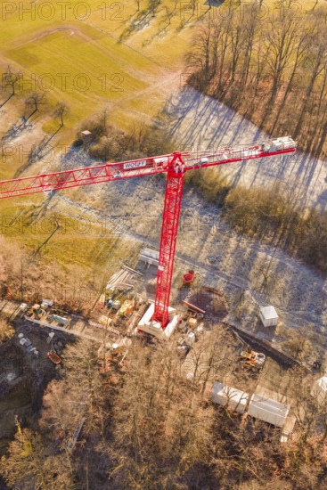 Red crane seen from the air on a construction site on the edge of a forest in an autumn landscape, construction of the Hermann Hesse Railway, Calw, Germany
