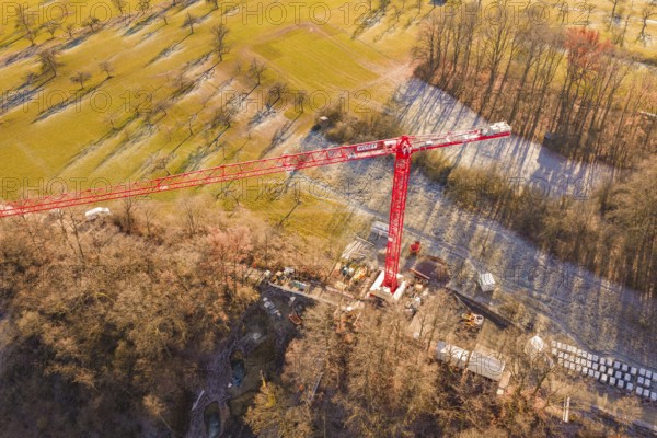 Red crane in the middle of a construction site, surrounded by autumnal landscape and meadows, construction of the Hermann Hesse Railway, Calw, Germany