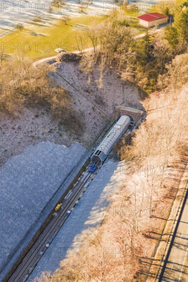 A Train Emerges from a Tunnel Surrounded by Forested Hills in a Wintry Setting, Construction of the Hermann Hesse Railway, Calw, Germany