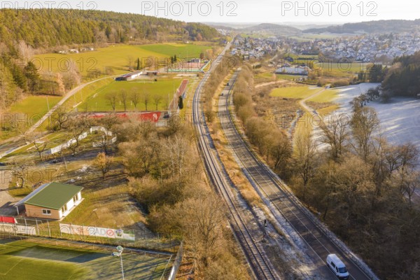 Aerial view of a railway running parallel to fields and a village nestled in a wintry landscape, construction of the Hermann Hesse Railway, Calw, Germany