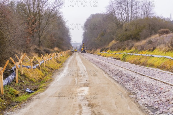 Landscape view of a road next to tracks with construction work and winter trees, construction of the Hermann Hesse Railway, Calw, Germany