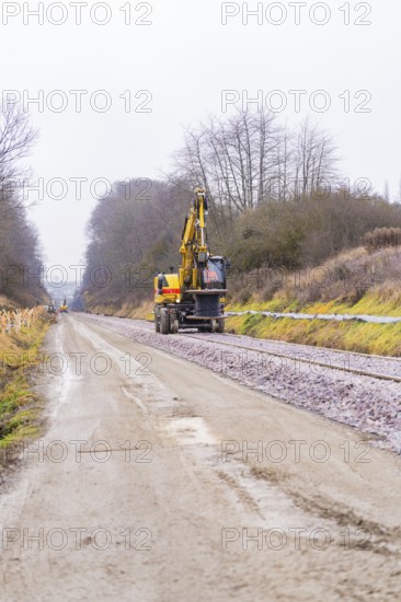 Railway tracks and an excavator on a construction site in a cloudy landscape, construction of the Hermann Hesse Railway, Calw, Germany