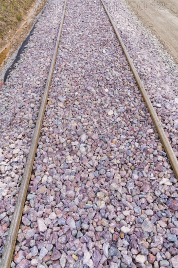 Detailed view of railroad tracks densely covered with grey and purple gravel, construction of the Hermann Hesse Railway, Calw, Germany