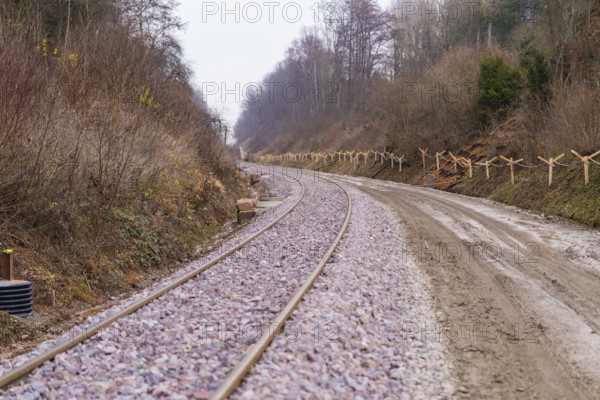 Curvy train tracks run through a quiet, wooded landscape with gravel, built by the Hermann Hesse Railway, Calw, Germany