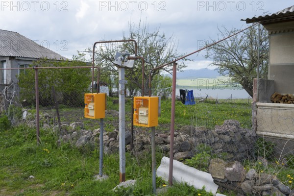 Two yellow gas meters next to a fence overlooking a lake and rural area, Sameba, Kvemo Kartli region, Lower Kartli, Georgia
