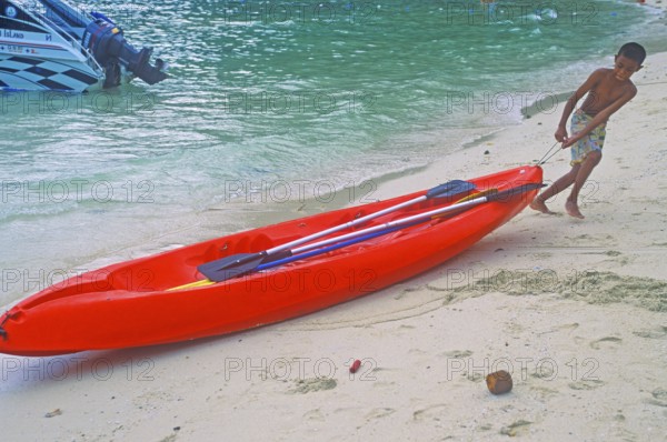 Boy pulls a kayak on the beach of Ko Phi Phi Don, two years in front of the tsunami, Thailand, December 2002, vintage, retro, old, historic