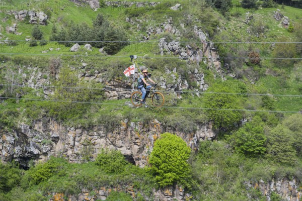 A bicycle ride on a rope leads across a rocky, green gorge, Dashbashi Gorge, Khrami River, Tsalka Nature Reserve, Kartli, Georgia