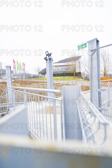 Entrance area with modern steel structure and flags, buildings in the distance, parking garage construction with charging infrastructure, Calw, Germany