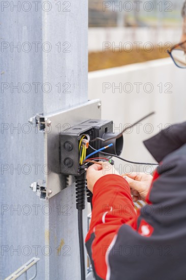 Person working on an electrical installation, cables are being connected, parking garage construction with charging infrastructure, Calw, Germany