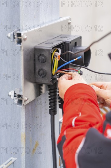 Detailed view of an electrician working on cables and connections, car park construction with charging infrastructure, Calw, Germany