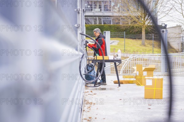Person working in the area with cables and boxes, building in the background, parking garage construction with charging infrastructure, Calw, Germany