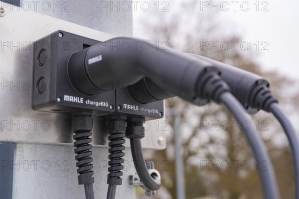 Two electronic chargers with cables on a metal bracket, parking garage construction with charging infrastructure, Calw, Germany