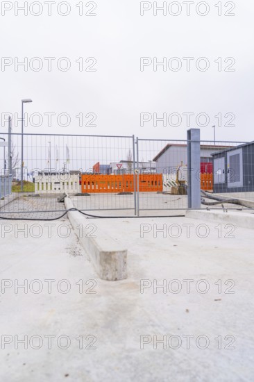 View of a cordoned off construction site with concrete floors and fences, parking garage construction with charging infrastructure, Calw, Germany