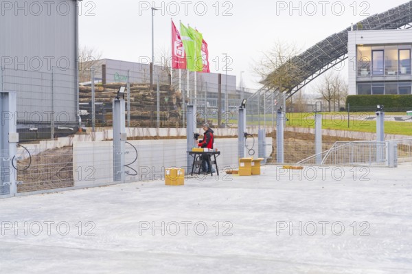 Two men sitting outdoors at a table on a construction site, parking garage construction with charging infrastructure, Calw, Germany
