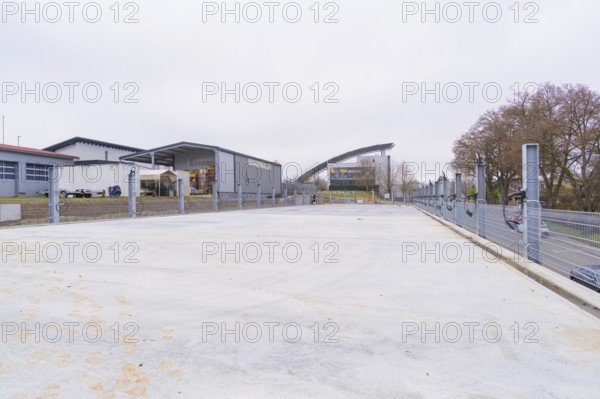 Industrial building in cloudy weather with an empty parking lot in the foreground, parking garage construction with charging infrastructure, Calw, Germany