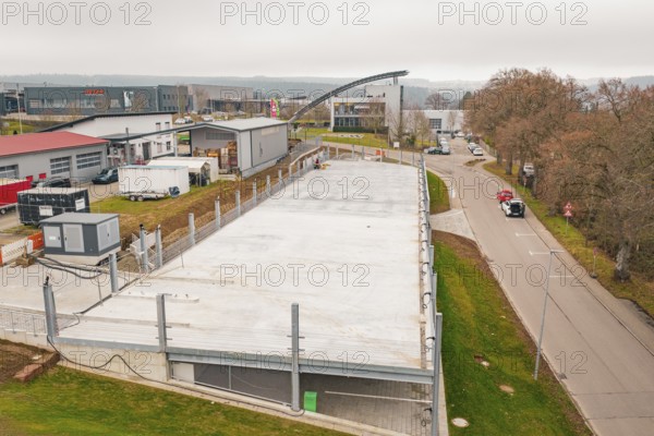 Aerial view of a large parking area in an industrial park, autumnal atmosphere, parking garage construction with charging infrastructure, Calw, Germany
