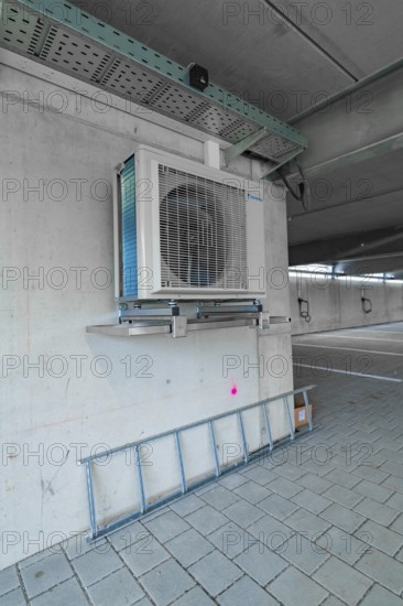Air conditioning system placed on a concrete wall and a ladder in a parking garage, parking garage construction with charging infrastructure, Calw, Germany