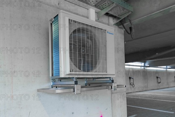 Air conditioner installed on an industrial bracket on a concrete wall indoors, parking garage construction with charging infrastructure, Calw, Germany