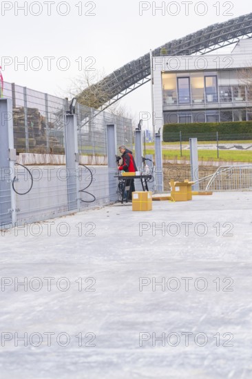 A worker sets up a table next to a fence with cables, boxes in the foreground, parking garage construction with charging infrastructure, Calw, Germany