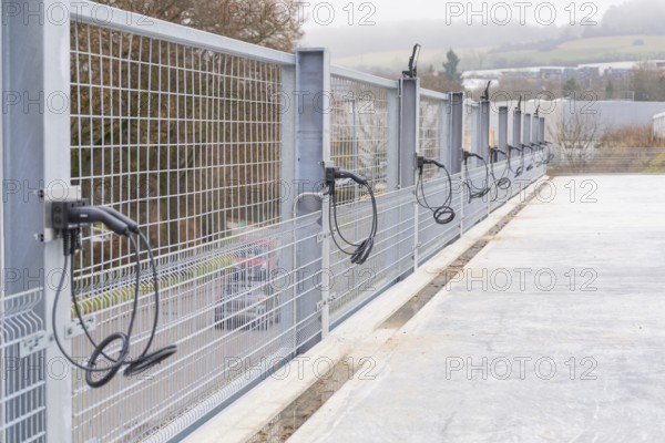 Cables run over a long fence on a concrete surface, with landscape in the background, parking garage construction with charging infrastructure, Calw, Germany