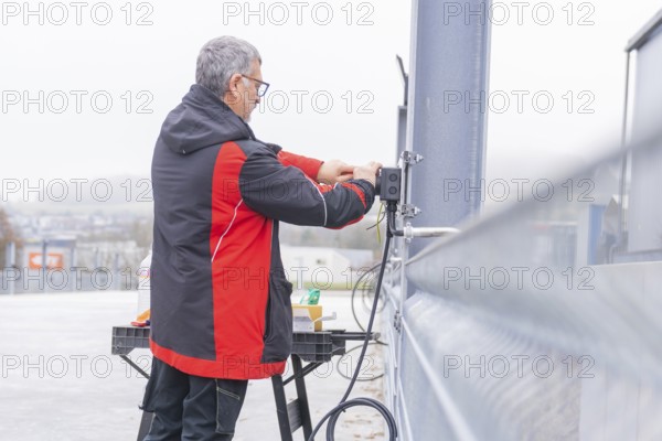 Person installing electrical cables in an industrial environment, parking garage construction with charging infrastructure, Calw, Germany