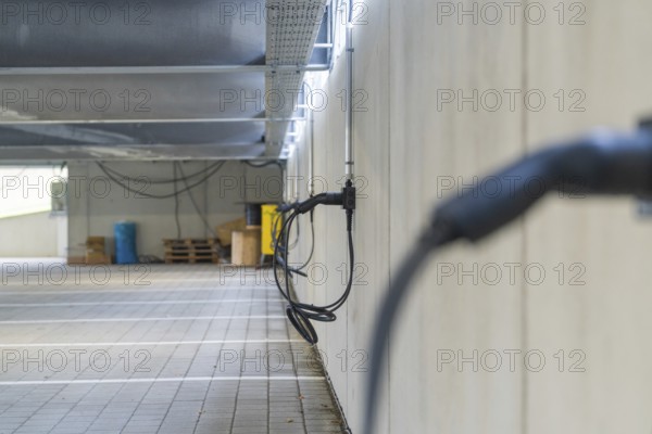 Electric charging cable on car park wall with concrete look, parking garage construction with charging infrastructure, Calw, Germany