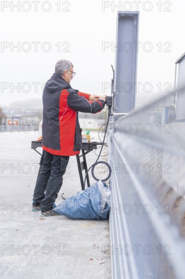 Man working on electrical cable installation in open area, parking garage construction with charging infrastructure, Calw, Germany
