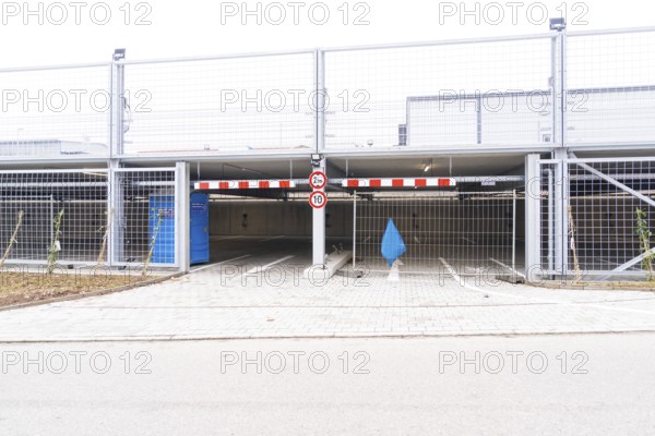 An empty parking deck with a barrier and a traffic sign. The area is secured by fences, car park construction with charging infrastructure, Calw, Germany