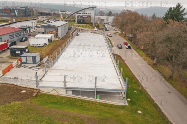 Aerial view of a parking lot next to a street in an urban environment, parking garage construction with charging infrastructure, Calw, Germany