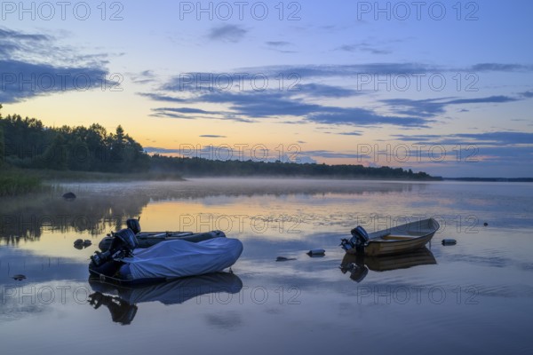 Two boats on a calm lake at sunset, Torne, Asnen National Park, Kronoberg, Sweden