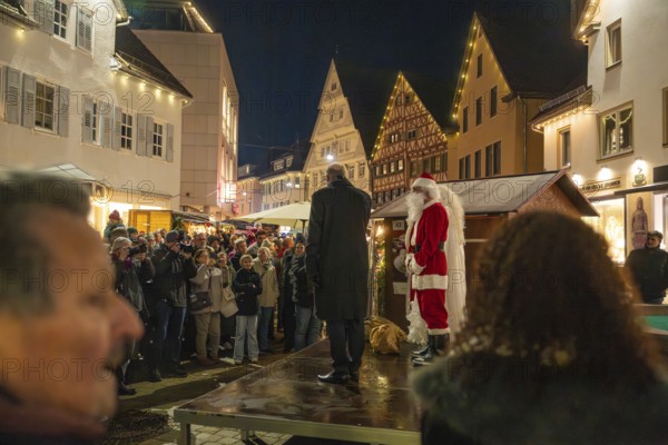 Santa Claus standing on stage in front of a crowd at night, Weihnachtsmark Nagold, LandkreiScalw, Germany