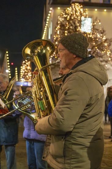 Tuba player in winter clothes on a street decorated with lights, Weihnachtsmark Nagold, LandkreiScalw, Germany
